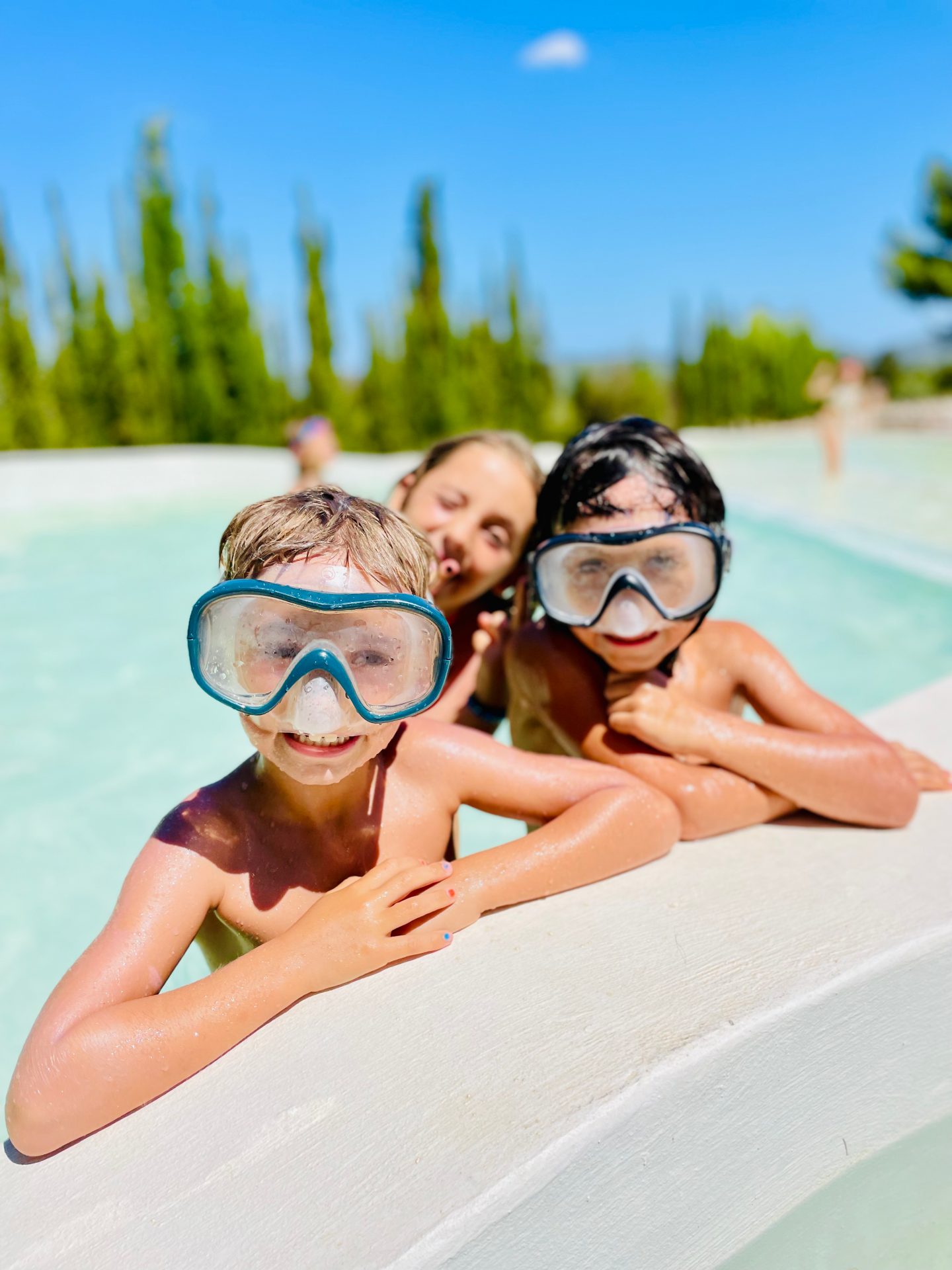 Tres jovenes sonriendo mientras se bañan en la piscina